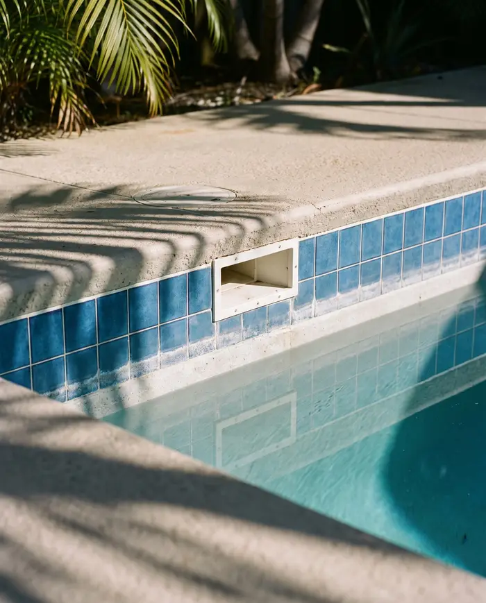 A pool with the water level well below its normal line, leaving a dry band of waterline tile exposed at the skimmer.